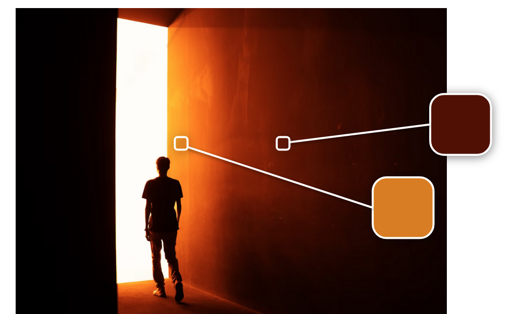 A man in silhouette walks through a dark hallway cast in orange toward a bright white light. A small square outlines part of the wall in shadow, connected to a dark brown color swatch. Another square appears on part of the wall close to the bright white light and connects to a goldfish orange color swatch. 
