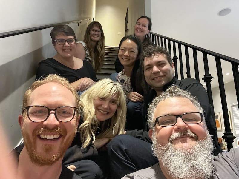 Eight smiling people seated on the stairs in a group photo.